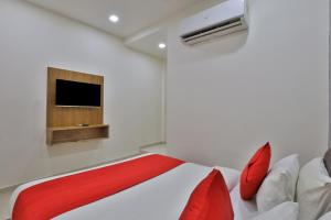 1 dormitorio con 1 cama y TV en la pared en Hotel Shivaay en Ahmedabad