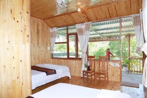 a bedroom with two beds and a balcony with windows at Phong Nha Midtown hotel in Phong Nha
