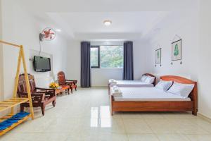 a living room with two beds and a tv at Hoa Cúc Phương Hotel Dĩ An - Bình Dương in Dĩ An