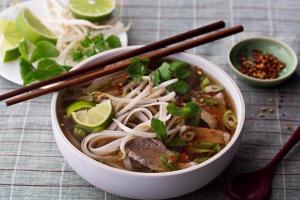 a bowl of soup with noodles and chopsticks on a table at Phong Nha Midtown hotel in Phong Nha