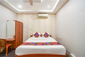 a bedroom with a large white bed with colorful pillows at FabHotel Saltlake Regency in Kolkata