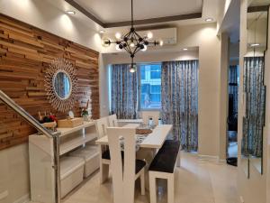 Huge condo unit near Burgos Circle, St Lukes, Shangri-La - P Hamptons T1 في مانيلا: غرفة طعام بحائط لكنة خشبية وطاولة وكراسي