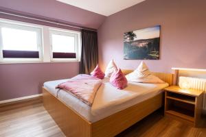 a bedroom with a bed with pink pillows on it at Heidetraum Pension & Ferienwohnung Arndt in Bispingen