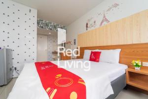 a bedroom with a white bed with a red blanket on it at RedLiving Apartemen Grand Sentraland - Bangde Rooms in Karawang