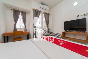 a bedroom with a bed and a tv and a desk at RedLiving Apartemen Grand Sentraland - Bangde Rooms in Karawang