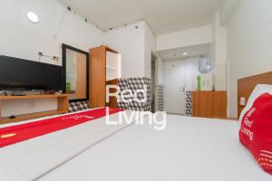 ein Wohnzimmer mit einem großen Bett und einem TV in der Unterkunft RedLiving Apartemen Grand Sentraland - Bangde Rooms in Karawang