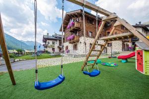 un parque infantil con columpios y una casa en Hotel Capriolo, en Livigno