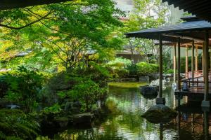 Kinugawa Grand Hotel Yumenotoki في نيكو: حديقة فيها بركة ومبنى