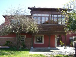 een rood huis met een balkon erop bij Hotel Rural La Curva Ribadesella in Ribadesella