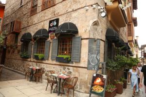 a woman walking past a building with tables and chairs at Gazetta in Antalya