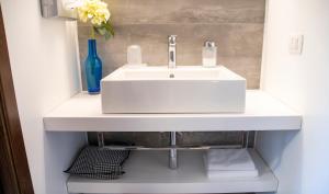 a bathroom with a white sink and a shelf at Feudogrande Bio Relais Hotel in Fiumefreddo di Sicilia