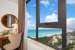 a room with a desk and a window with a view of the beach at Paris Deli Danang Beach Hotel in Danang