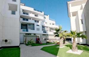 un immeuble d'appartements blanc avec une aire de jeux en face. dans l'établissement Modern 3 Bedroom 7 Guests Sun Golf Beach Apartments, à Villacosta