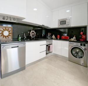 cocina con armarios blancos, lavadora y secadora en Modern 3 Bedroom 7 Guests Sun Golf Beach Apartments, en Villacosta