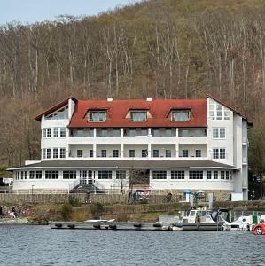 ein großes weißes Gebäude mit rotem Dach neben dem Wasser in der Unterkunft Terrassenhotel Seepromenade in Edersee