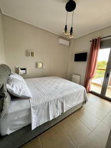 een slaapkamer met een wit bed en een raam bij EVa's Luxury Apartments No 2 in Áyios Spirídhon