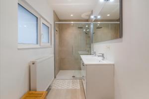 a white bathroom with a shower and a sink at Maison les Bruyères 1 - Luxueus wonen Blankenberge in Blankenberge