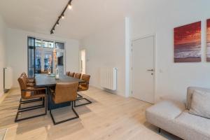 - une salle à manger avec une table et un canapé dans l'établissement Maison les Bruyères 1 - Luxueus wonen Blankenberge, à Blankenberge