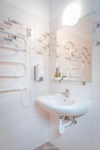 een witte badkamer met een wastafel en een douche bij City Inn Szigetvar in Szigetvár