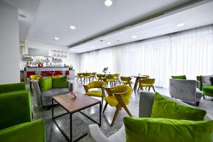 un restaurante con muebles verdes, mesas y sillas en Europe Hotel, en Ereván