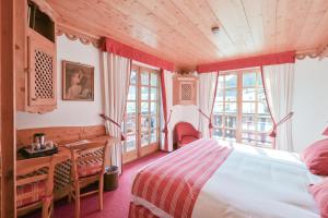 a bedroom with a bed and a desk and windows at Hôtel Chalet Saint-Georges in Megève