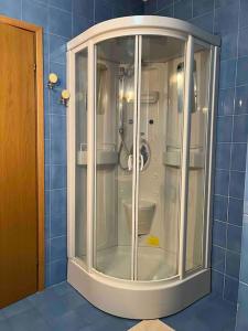 a glass shower in a blue tiled bathroom at Este Stay in Este