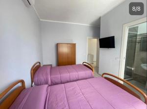a bed with purple sheets in a room at Sweet Stay in Fiumicino
