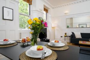 una sala de estar con una mesa con un jarrón de flores en 2 Bedr, 3 Beds, 1 Bath Thames, Trafalgar SQ, en Londres