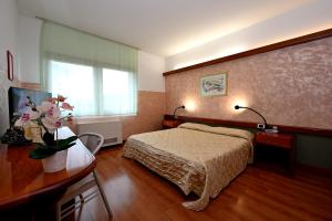 Hotel Italia في مونفالكوني: غرفة في الفندق بها سرير وطاولة بها زهور