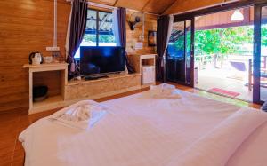 a bedroom with a large white bed with a television at Lipe Garden Beach Resort in Ko Lipe