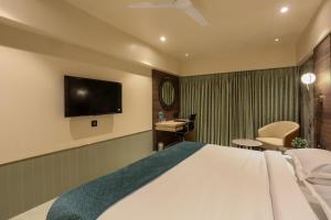 a hotel room with a bed and a flat screen tv at Hotel Corporate in Navi Mumbai