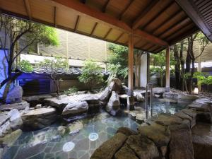 a pool in a backyard with rocks and a waterfall at Hamanoyu in Suwa