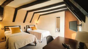 Cette chambre comprend 2 lits, une table et une télévision. dans l'établissement Auberge Saint Jacques, à Conques