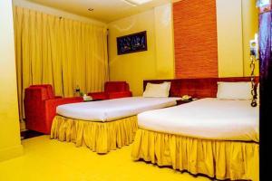 a hotel room with two beds and a chair at Royal Living Hotel & Suites in Chittagong
