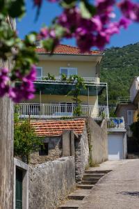 a house on a hill with purple flowers in the foreground at Pelješac Apartmani -Orsula in Kučište