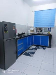 cocina con armarios azules y nevera negra en NADI HOMESTAY MELAKA, en Air Molek