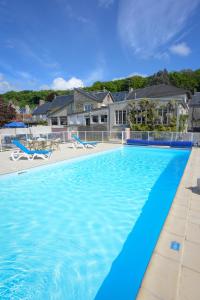 a swimming pool with blue water in front of a house at Hotel Des Bains in Saint-Jean-le-Thomas