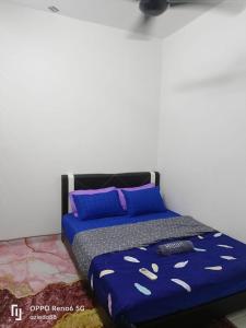 1 cama con edredón azul y almohadas azules en NADI HOMESTAY MELAKA, en Air Molek