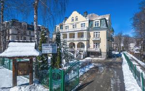 a large house with a green fence in the snow at Jasny Pałac in Zakopane