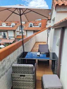 a table and chairs on a balcony with an umbrella at Fabuloso apartamento con terraza y piscina in Villabáñez