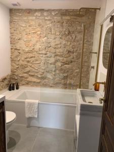 a bathroom with a white tub and a stone wall at Casa Valleta in Tivenys