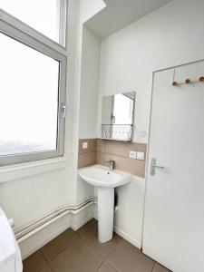a white bathroom with a sink and a mirror at ROME - Studio meublé à Reims in Reims