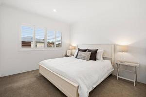 um quarto branco com uma cama grande e uma janela em Modern Minimalistic Home 3BR em Perth