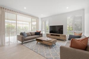 a living room with a couch and a tv at Modern Minimalistic Home 3BR in Perth