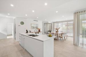 cocina blanca con mesa y comedor en Modern Minimalistic Home 3BR, en Perth