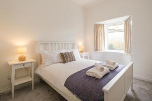 a bedroom with a white bed with towels on it at The Lodge, Aldringham in Aldringham
