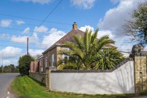 a brick house with a fence and a palm tree at The Lodge, Aldringham in Aldringham