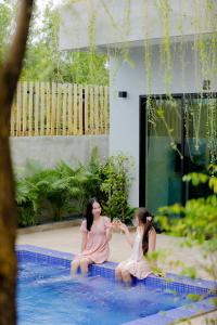 two women sitting in the water in a pool at Rainforest Hotel by NSUN in Kampot