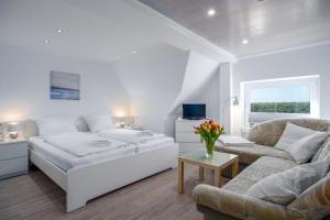 a white living room with a bed and a couch at Deichhus Nordseeliebe direkt am Deich - Nordsee - Dagebüll - Am Vogelreservat in Dagebüll