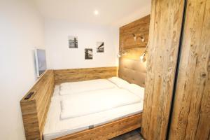 a bed in a room with a wooden wall at Ferienwohnung Königsleiten 28 - Top 36 in Wald im Pinzgau